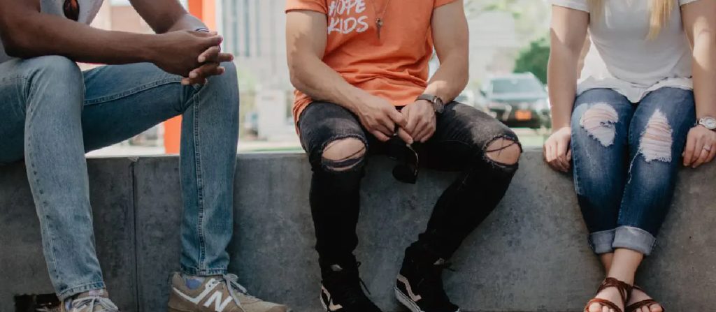Close crop of 3 people sitting on a wall