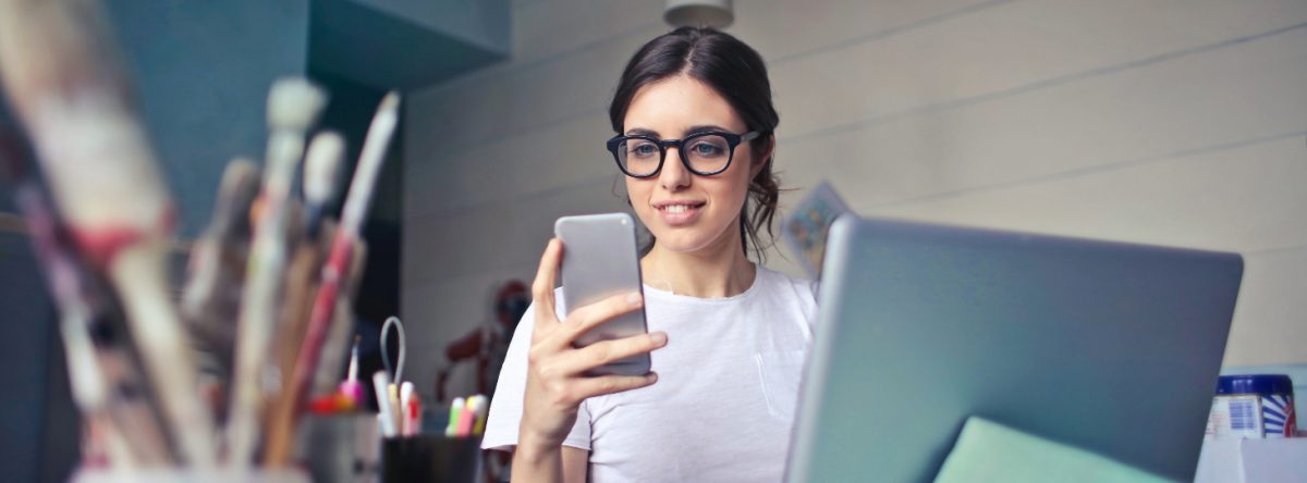 Woman in office-cum-art studio looks at mobile phone