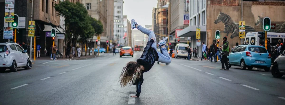 Woman spins on hand in middle of a city street, breakdance style