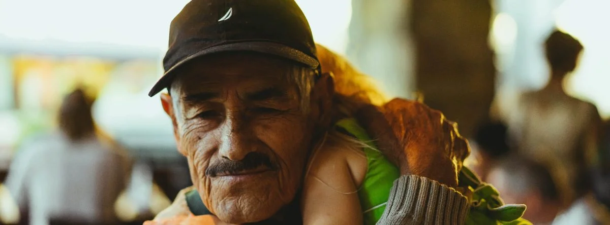 Old man carries sleeping child at a festival